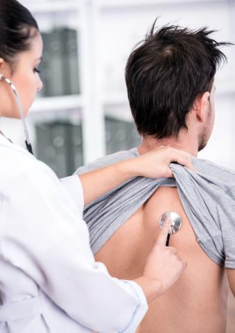 A doctor uses a stethoscope on a patients back