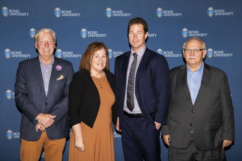 Panellists Jeremy Cooper, Deborah Ralston, Michael O'Neill and Ron Bird standing in front of a Bond University banner