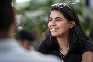 A student sitting in the Atrium smiling at another student