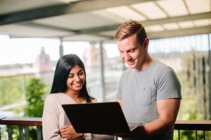 Two students standing looking at a laptop screen