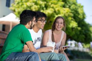 Three students sit on steps on the Bond Campus